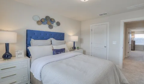 a bedroom with a bed and a lamp on dresser