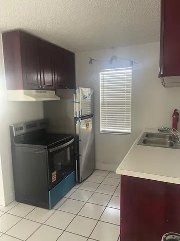 a kitchen with granite countertop a sink stove and refrigerator