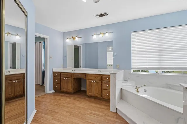 a spacious bathroom with a tub sink shower and mirror