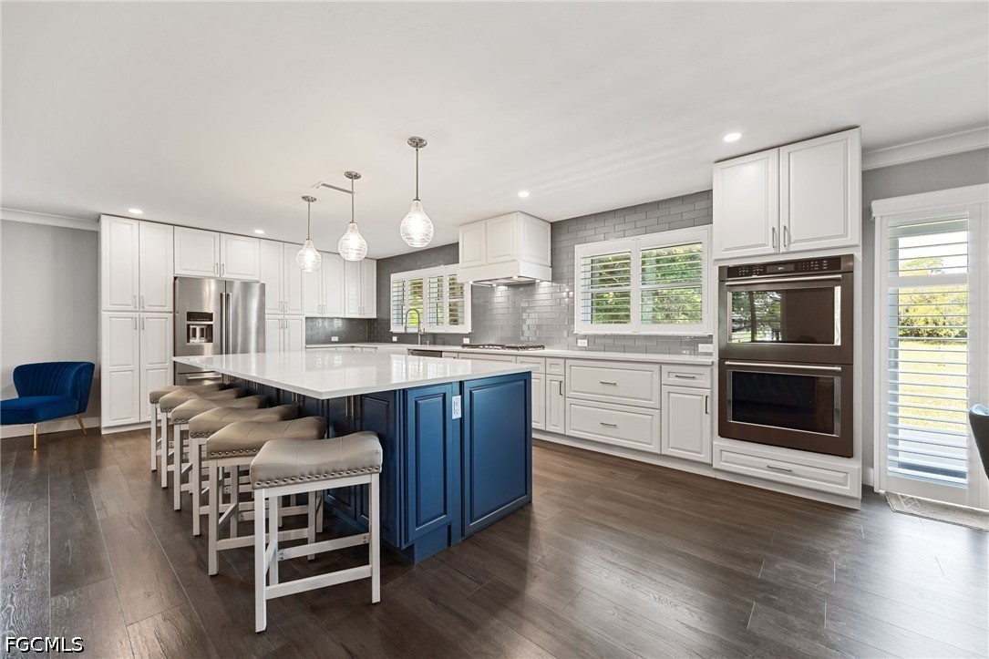 4220 Staley Road Fort Myers, FL 33905 - Photo 14 of 47 a kitchen with stainless steel appliances kitchen island granite countertop a stove a sink dishwasher a dining table and chairs with wooden floor