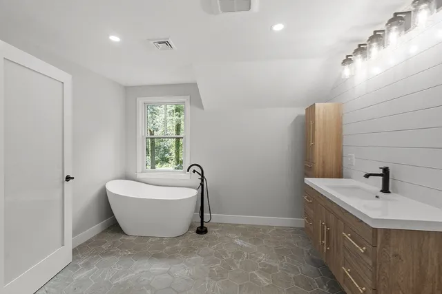 a bathroom with a double vanity sink a bathtub and window