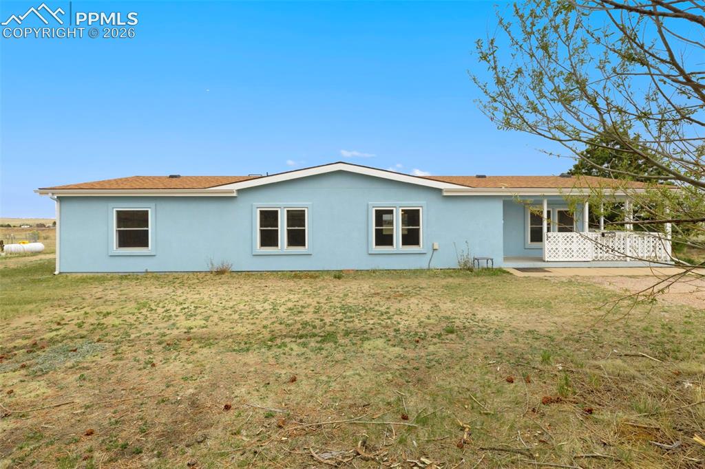 13335 Gymkhana Road Peyton, CO 80831 - Photo 34 of 38 Light blue exterior featuring multiple windows and a covered porch with white lattice railing