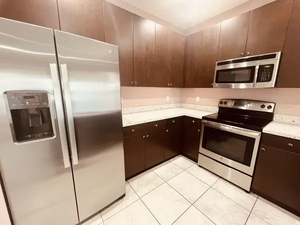 a kitchen with stainless steel appliances kitchen island granite countertop a refrigerator a stove and a sink with wooden floor