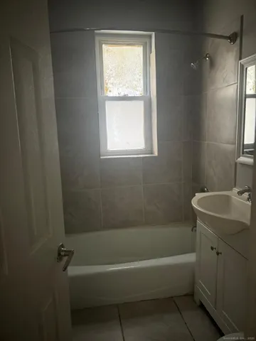 a bathroom with a sink a bathtub window and shower