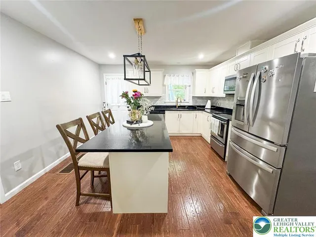 a kitchen with refrigerator and wooden floor