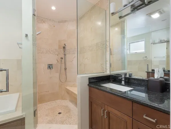 a bathroom with a granite countertop sink a mirror a bathtub and shower