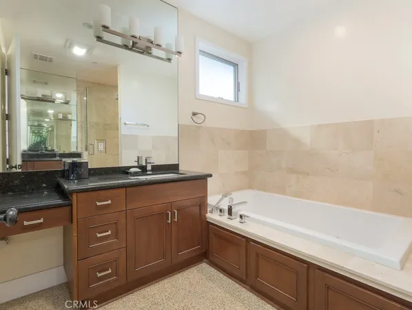a bathroom with a granite countertop bathtub a sink and a mirror