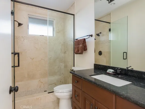 a bathroom with a granite countertop sink toilet and shower