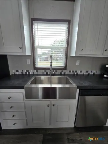 a kitchen with granite countertop white cabinets and sink