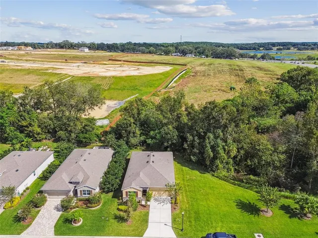 an aerial view of residential house with outdoor space and trees all around