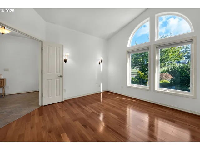 a view of an empty room with a window and wooden floor
