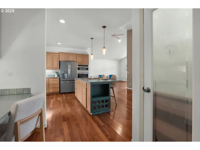 a living room with stainless steel appliances kitchen island granite countertop a refrigerator and a sink