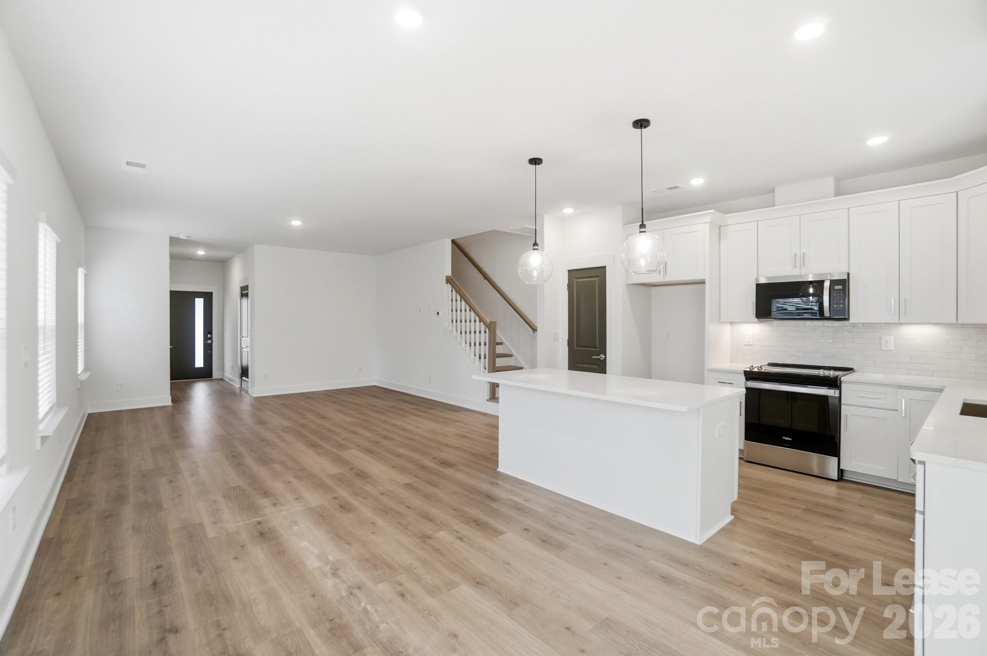 3945 Tillman Road Charlotte, NC 28208 - Photo 12 of 47 a large white kitchen with stainless steel appliances kitchen island granite countertop a stove a refrigerator a sink and a oven with wooden floor