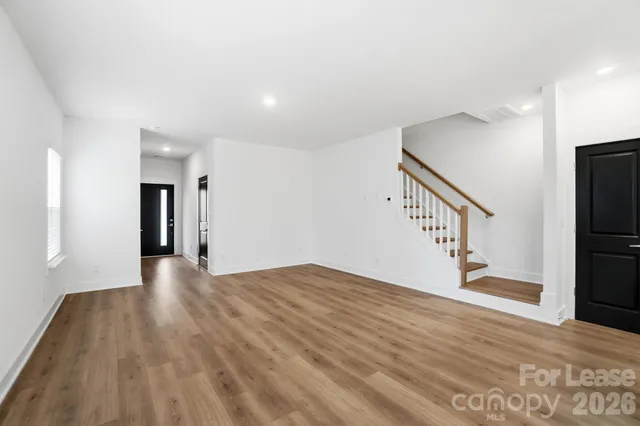 a view of an empty room with wooden floor and stairs