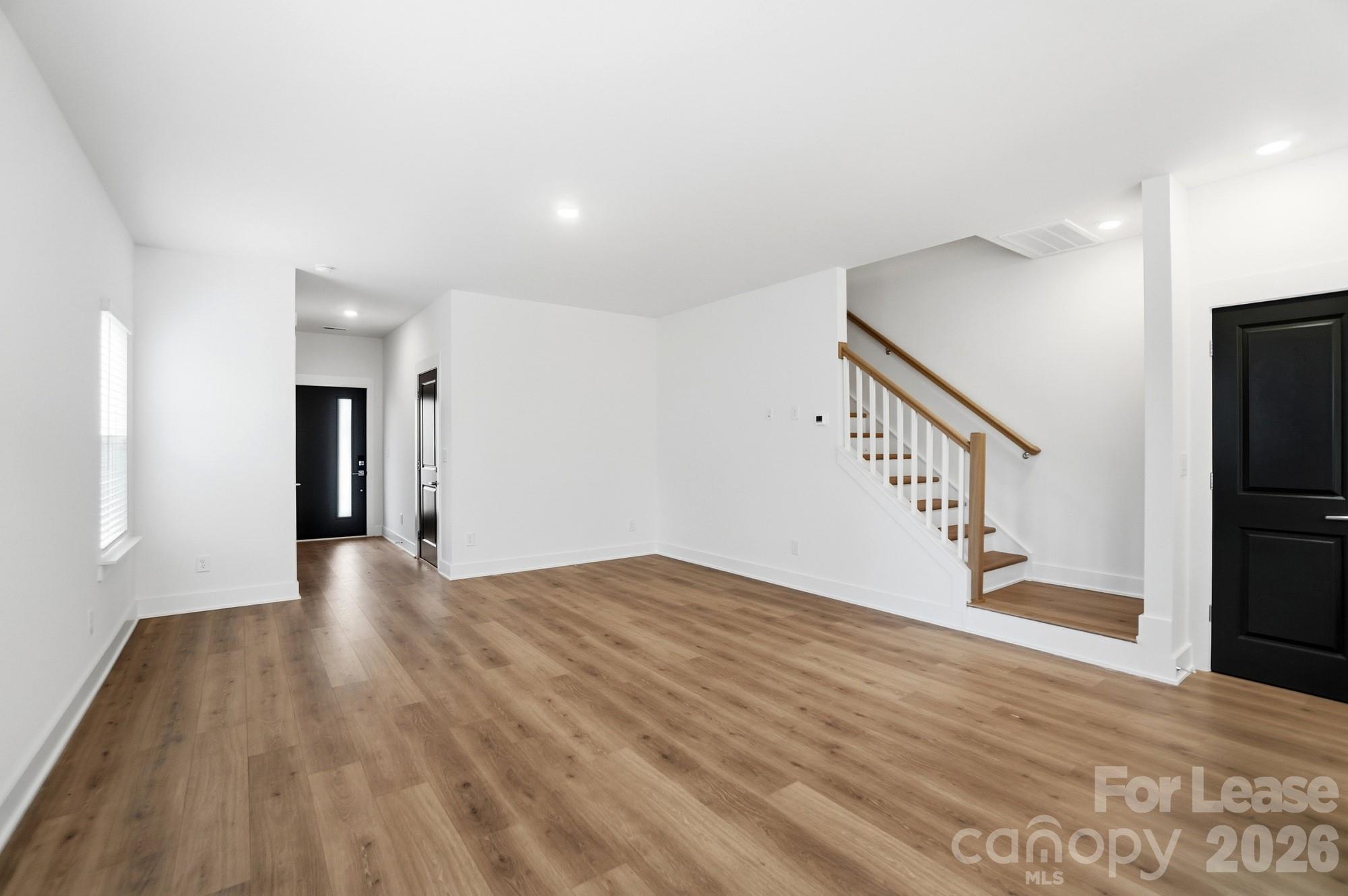 3945 Tillman Road Charlotte, NC 28208 - Photo 7 of 47 a view of an empty room with wooden floor and stairs