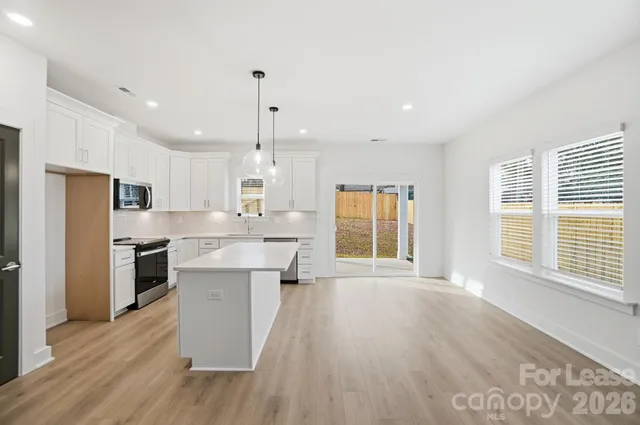 a large kitchen with large windows and wooden floor