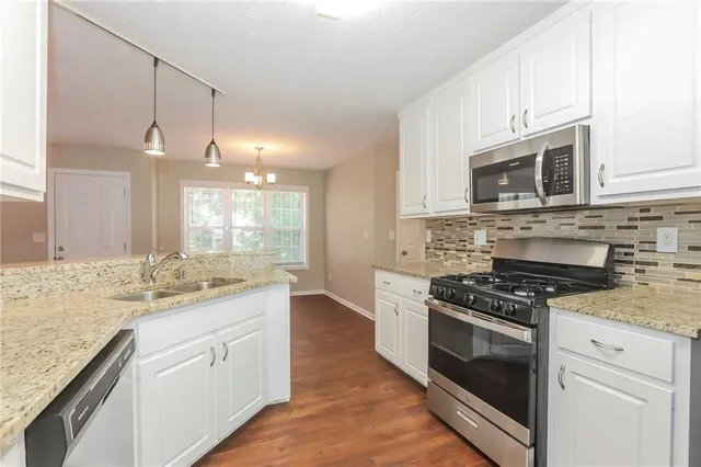 a kitchen with stainless steel appliances granite countertop a stove a sink and a microwave