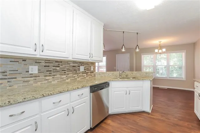 a kitchen with granite countertop a sink white cabinets and white appliances