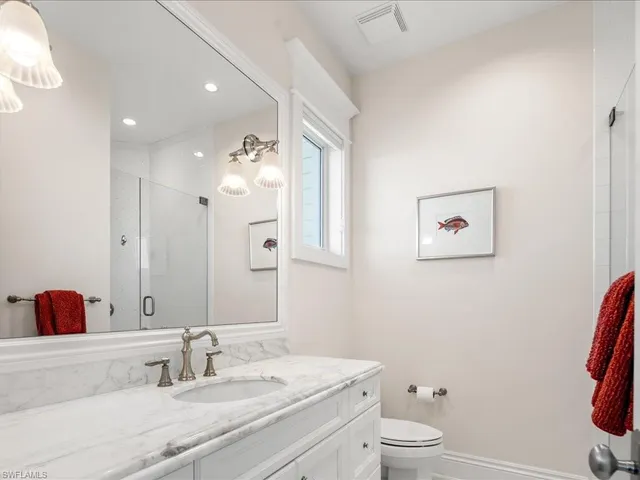 a bathroom with a granite countertop sink mirror vanity and toilet