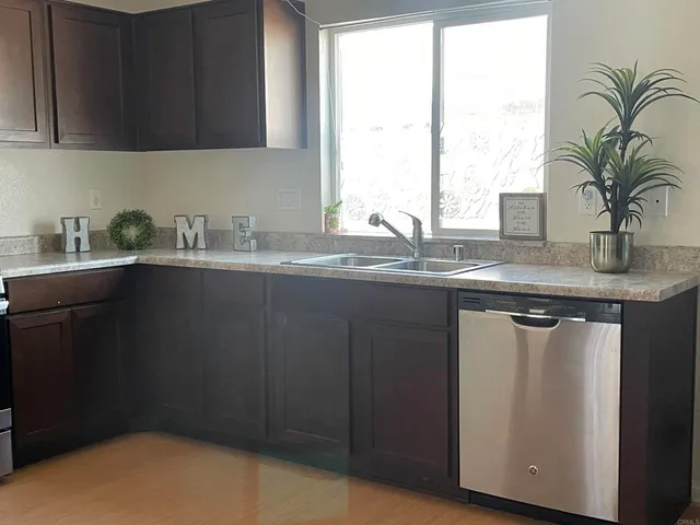 a kitchen with stainless steel appliances granite countertop a sink a window and a counter