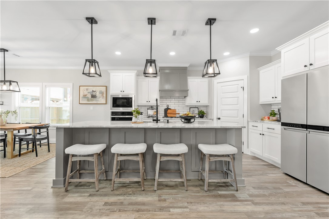 2905 GOLDBERG Drive Bryan, TX 77808 - Photo 7 of 31 a kitchen with stainless steel appliances kitchen island granite countertop a dining table chairs and white cabinets