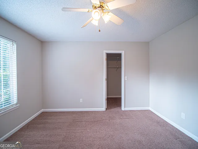 an empty room with chandelier fan and windows