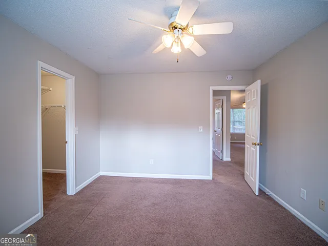 an empty room with closet and a ceiling fan