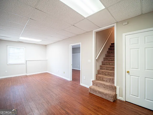 a view of an empty room with wooden floor and stairs