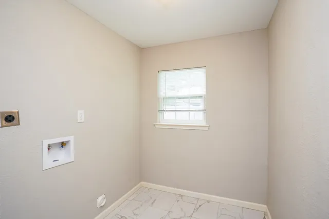 a brick house with a yard plants and large tree