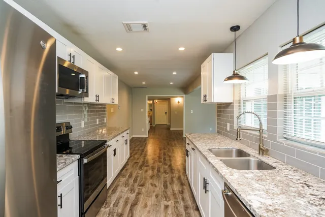 a kitchen with stainless steel appliances granite countertop a sink stove and refrigerator