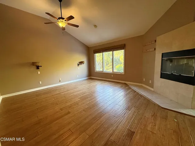 a view of an empty room with a window and wooden floor