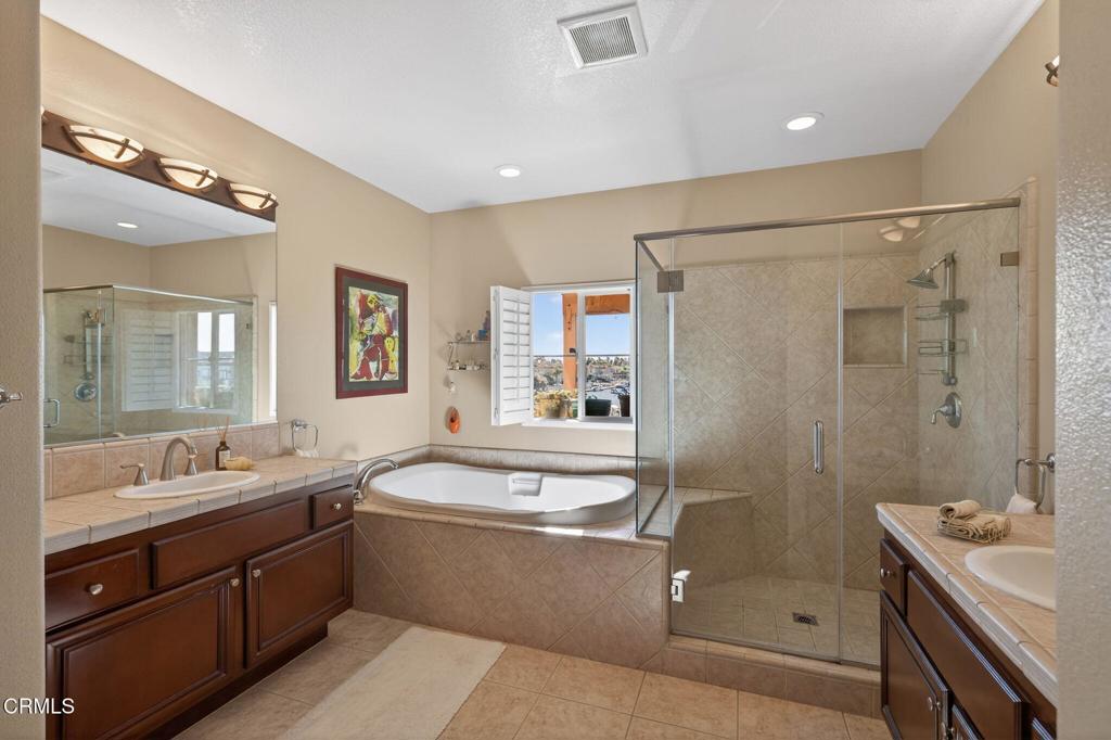 4337 Admiral Way Oxnard, CA 93035 - Photo 34 of 67 a large bathroom with a double vanity sink a large mirror and a bathtub