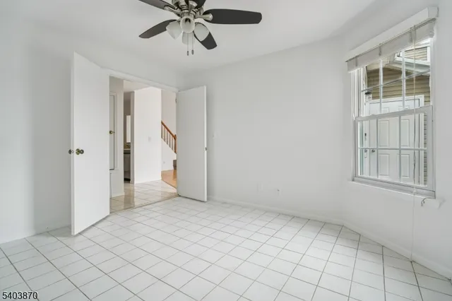 an empty room with chandelier fan and windows