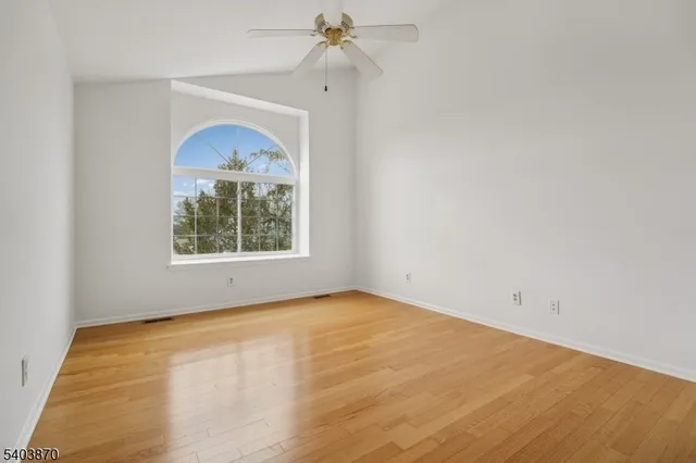 an empty room with a window and a ceiling fan