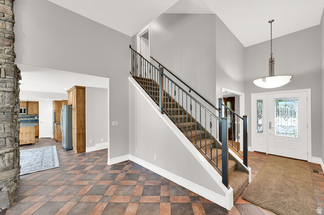 4792 Glasmann Way South Ogden, UT 84403 - Photo 37 of 70 Two-story foyer featuring an ornate entry door with decorative glass, a staircase with wrought iron balusters, a stone fireplace, and patterned floor tiling