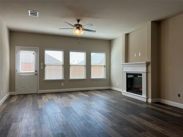 an empty room with wooden floor chandelier and windows
