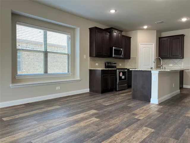 a view of kitchen with kitchen island stainless steel appliances a sink and a stove