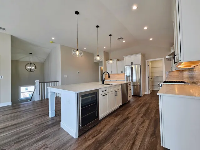 a large kitchen with kitchen island a stove a sink a refrigerator and a fireplace