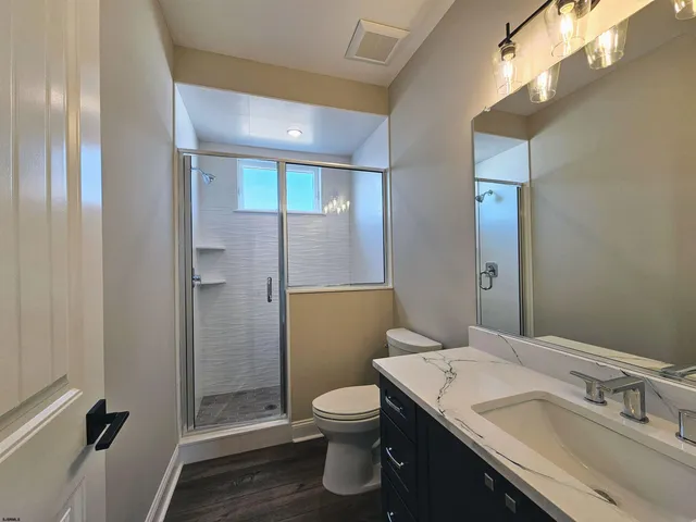 a bathroom with a granite countertop sink toilet a mirror and shower