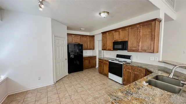 a kitchen with granite countertop a refrigerator and a stove top oven