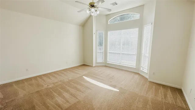 an empty room with a windows and chandelier fan