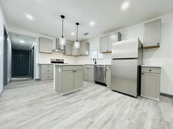 a kitchen with stainless steel appliances granite countertop a sink a stove and a wooden floors