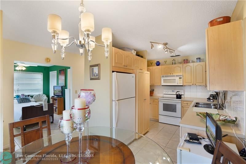 8625 Boca Drive, Unit 12 Boca Raton, FL 33433 - Photo 9 of 42 a kitchen with a refrigerator a stove top oven a dining table and chairs