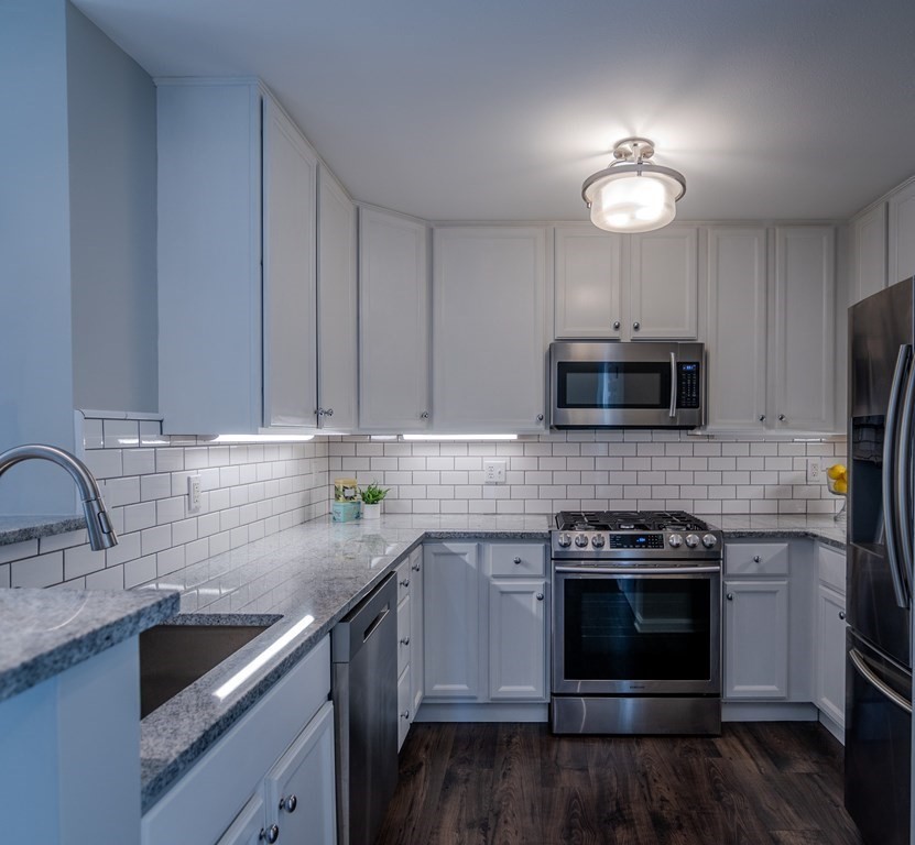 38 Village Road, Unit 615 Middleton, MA 01949 - Photo 2 of 23 a kitchen with stainless steel appliances granite countertop a sink stove and microwave