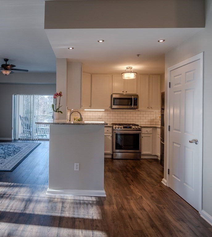 38 Village Road, Unit 615 Middleton, MA 01949 - Photo 3 of 23 a kitchen with kitchen island a counter top space a sink stainless steel appliances and cabinets