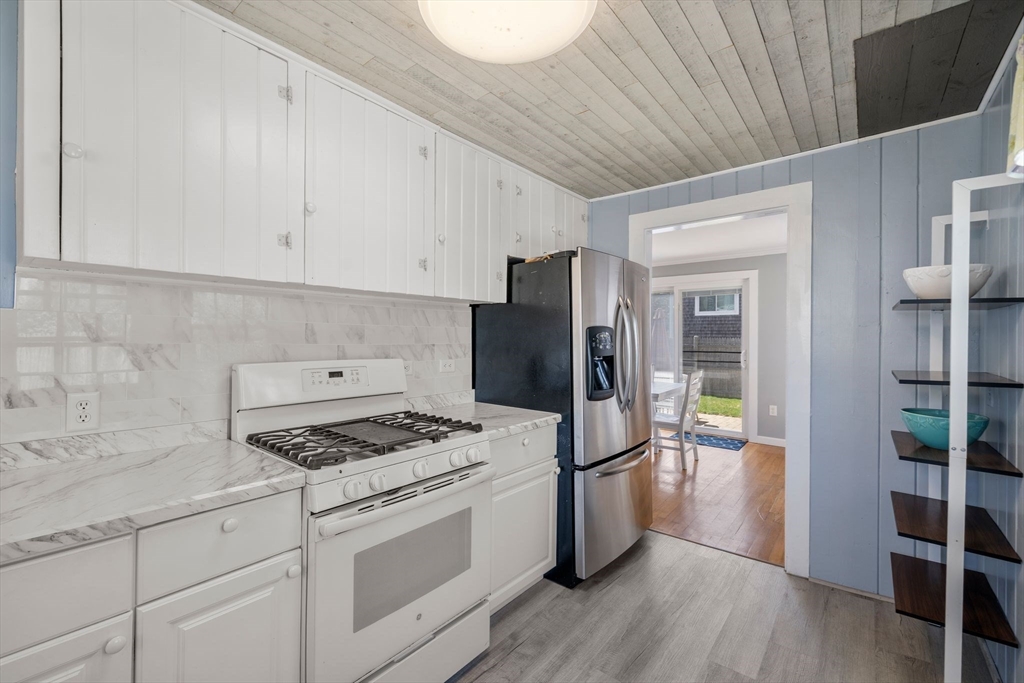13 Hamilton Road Dennis, MA 02639 - Photo 26 of 40 a kitchen with granite countertop a refrigerator a stove a sink dishwasher and white cabinets with wooden floor