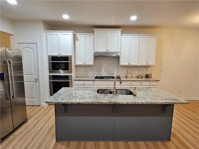 a kitchen with kitchen island granite countertop a sink stove and refrigerator