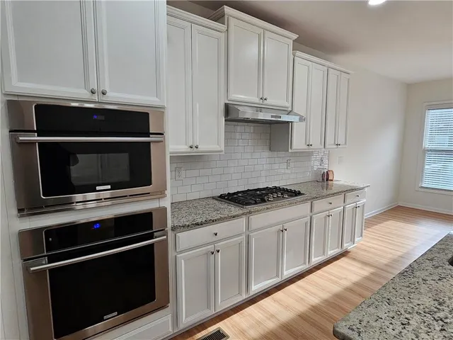 a kitchen with granite countertop white cabinets and stainless steel appliances