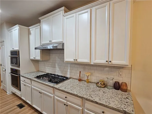 a kitchen with granite countertop a stove sink and cabinets