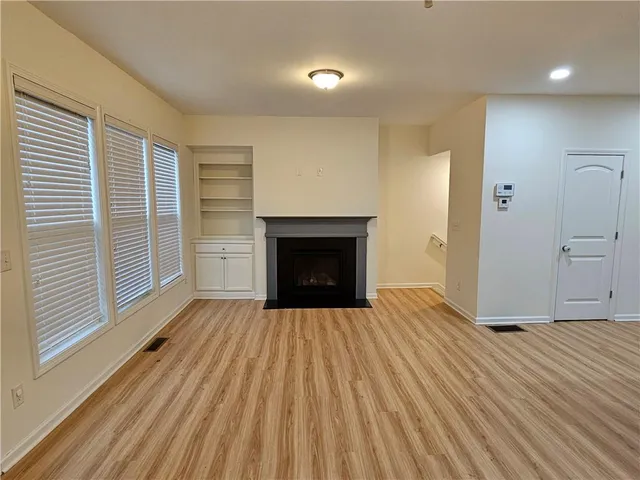 an empty room with wooden floor a fireplace and windows